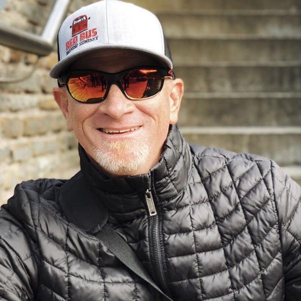 Carl Rettinger smiling in a ball cap and sunglasses.
