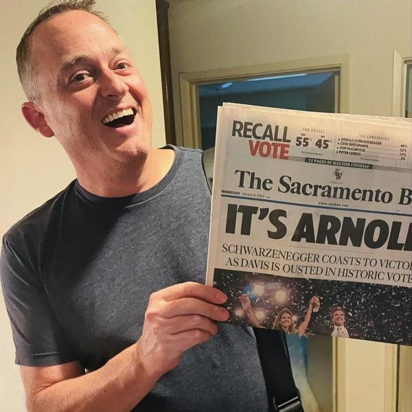 William Foster, laughing, holds up a Sacramento Bee front page that reads It's Arnold.